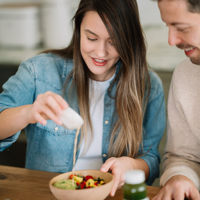 Cuplu pregătind o masă sănătoasă cu salate proaspete și sucuri Juiceit, simbolul unui stil de viață echilibrat și sănătos.