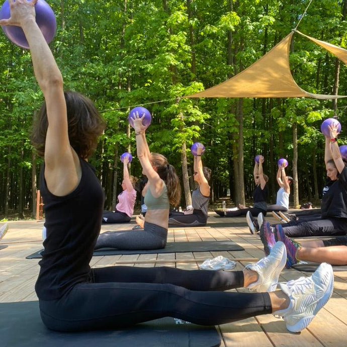 Participanți la un retreat Juiceit practicând pilates în aer liber, într-un cadru natural liniștit.