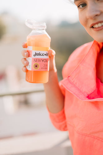 Femeie ținând în mână un suc Juiceit New You, perfect pentru programul de detoxifiere și un stil de viață sănătos