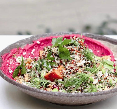 Bol nutritiv de quinoa cu legume proaspete, ierburi aromatice și hummus de sfeclă roșie, servit în cadrul unui retreat dedicat sănătății și wellbeing-ului.