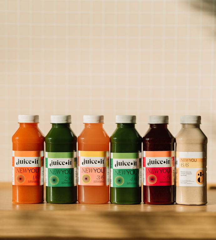 Set complet de sucuri Juiceit New You așezate pe o masă, cu etichete colorate care evidențiază ingrediente naturale pentru un stil de viață sănătos. Perfect pentru hidratare și prospețime zilnică.