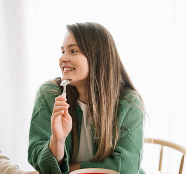 Femeie savurând o supă cremă de sfeclă roșie, decorată cu semințe, alături de crutoane sănătoase, într-un moment de relaxare la masă.