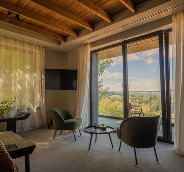 Dormitor într-un retreat montan, cu tavan din lemn, pat confortabil, decor cald și vedere panoramică spre peisajele din Munții Bucegi.