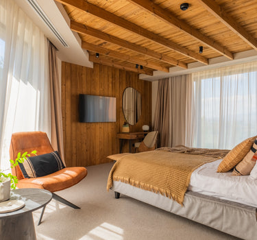 Cameră de retreat cu design minimalist, fotolii verzi, decor natural și ferestre mari ce oferă priveliști spectaculoase spre natura montană.”

